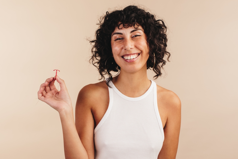 woman holding up an IUD.